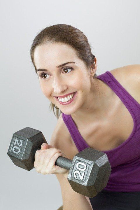 a girl with dumbbells performs an exercise to lose weight